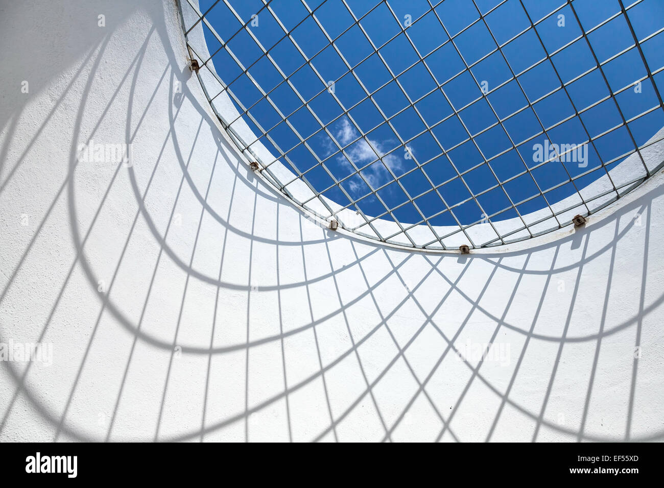 Résumé de l'intérieur blanc fragment. Ciel bleu derrière la fenêtre ronde avec grille métallique Banque D'Images