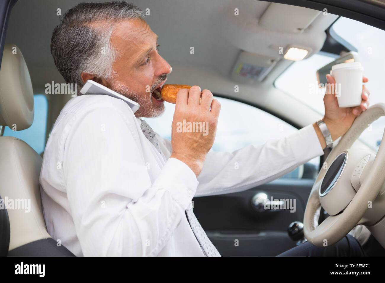 L'homme de boire du café et manger donnut sur le téléphone Banque D'Images