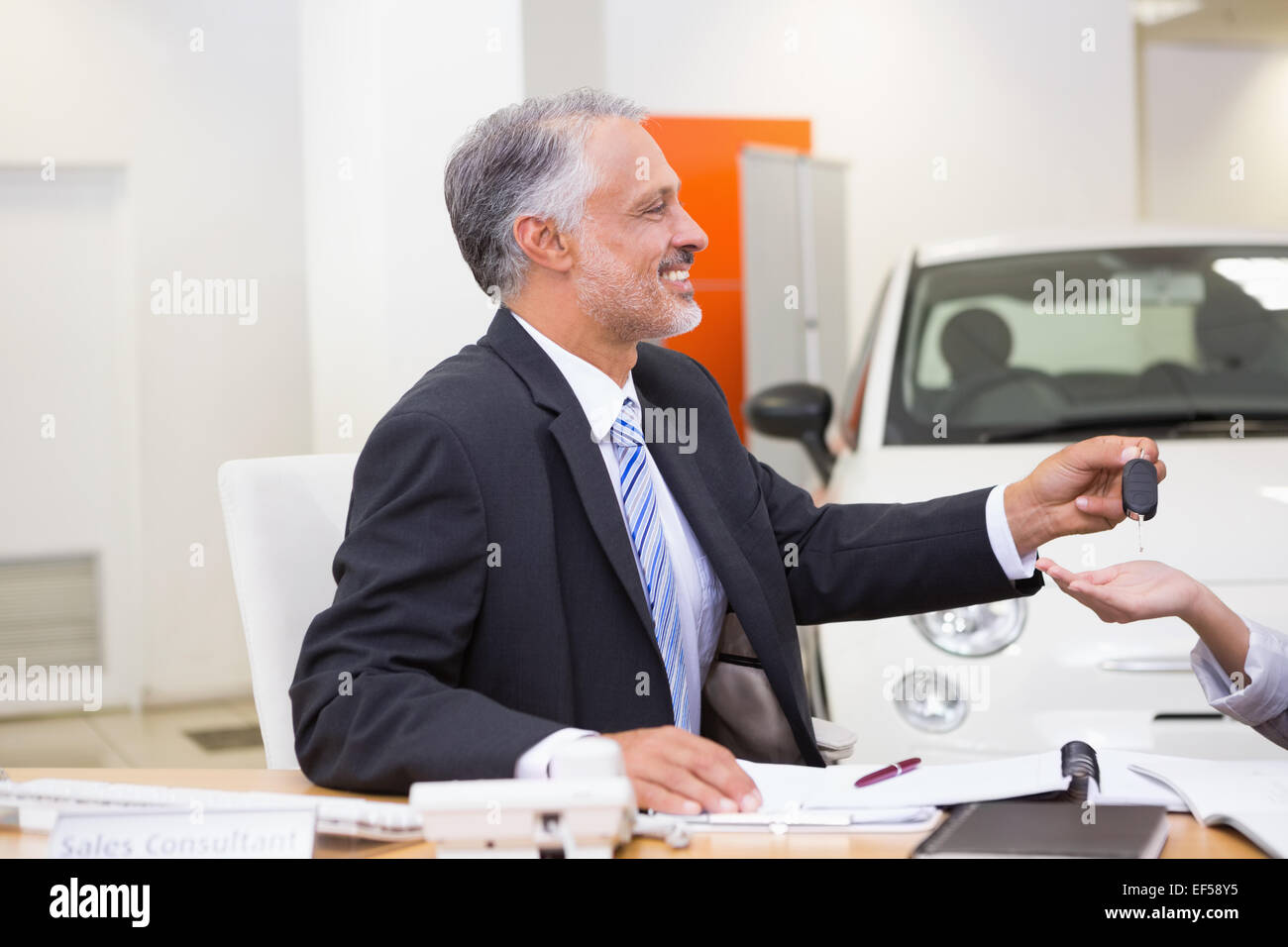 Smiling salesman donnant les clés de la voiture d'un client Banque D'Images