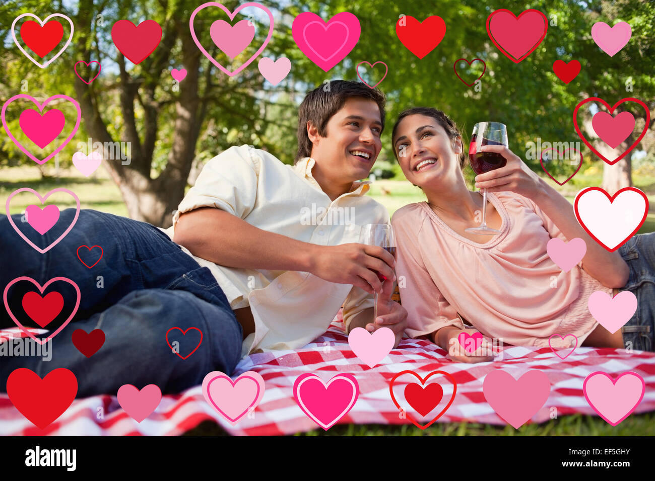 Image composite de deux amis à la recherche dans la distance tout en maintenant les verres au cours d'un pique-nique Banque D'Images