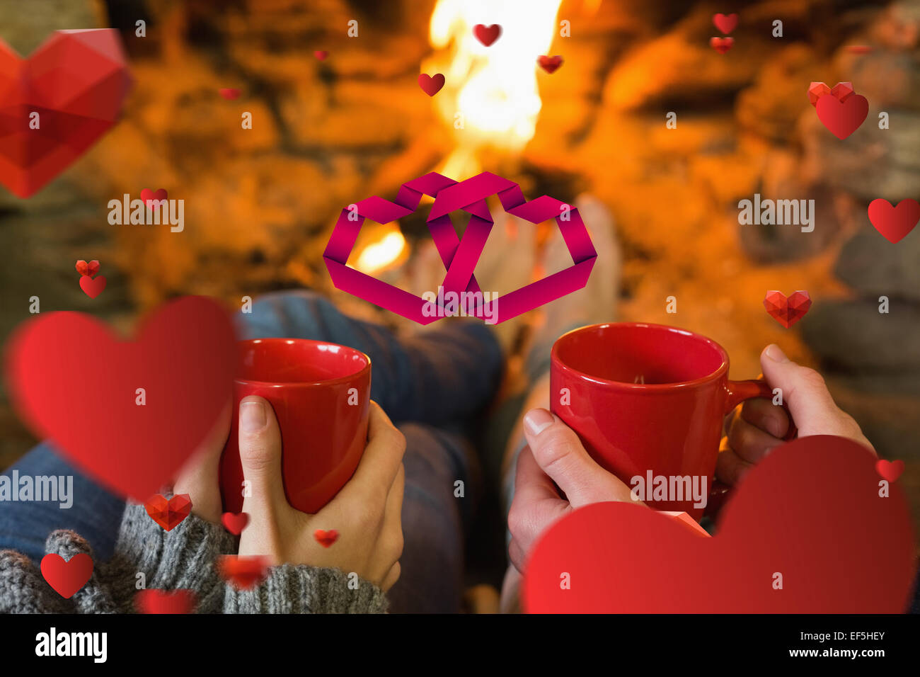 Image composite des mains avec les tasses de café rouge en face d'une cheminée allumée Banque D'Images Image composite des mains avec les tasses de café rouge en face d'une cheminée allumée Banque D'Images