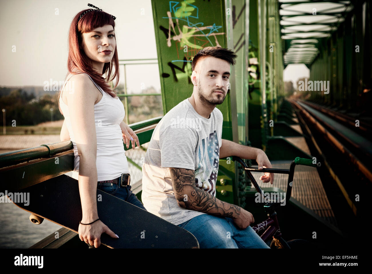 Jeune couple avec Skateboard and BMX bicycle outdoors Banque D'Images
