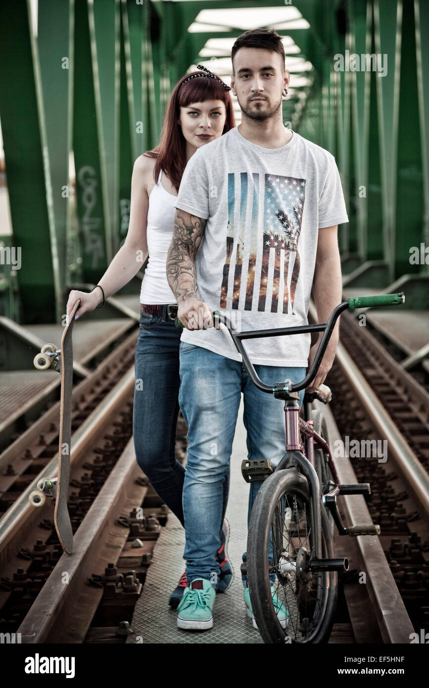 Jeune couple avec Skateboard and BMX bicycle outdoors Banque D'Images