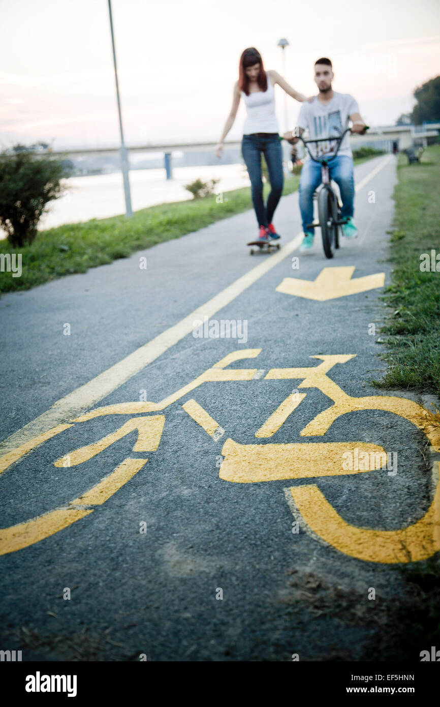 Jeune couple avec Skateboard and BMX bicycle outdoors Banque D'Images