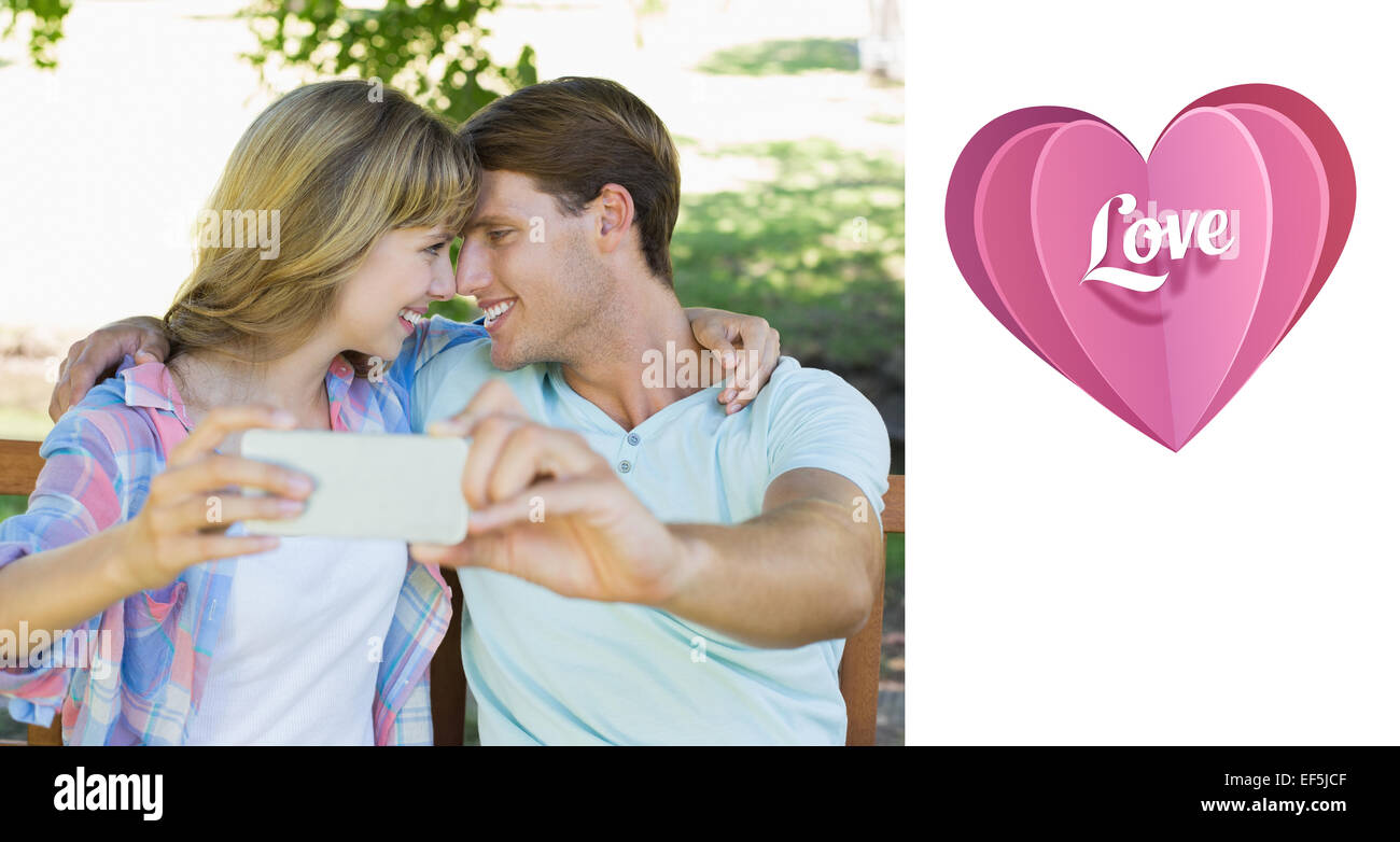 Image composite de smiling couple assis sur un banc dans le parc en prenant un selfies Banque D'Images