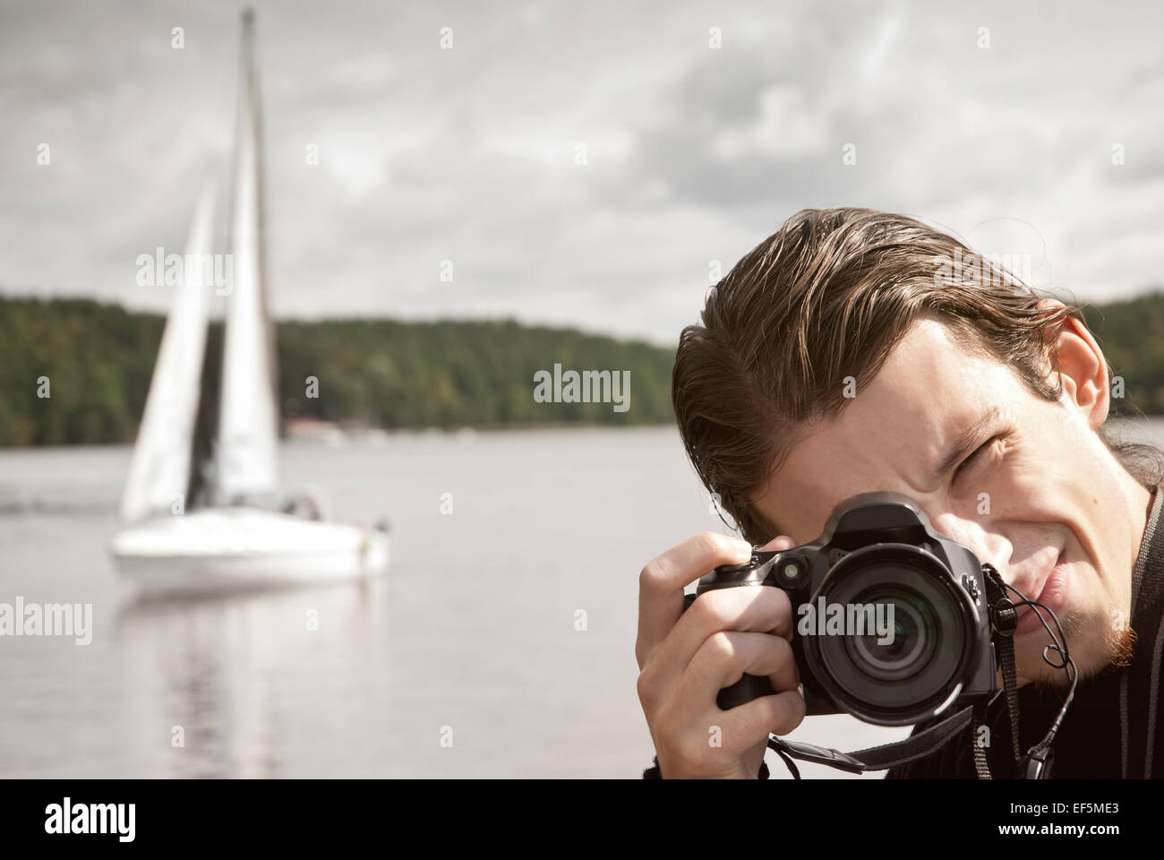 Jeune homme européen prenant photo de bateau à voile Banque D'Images