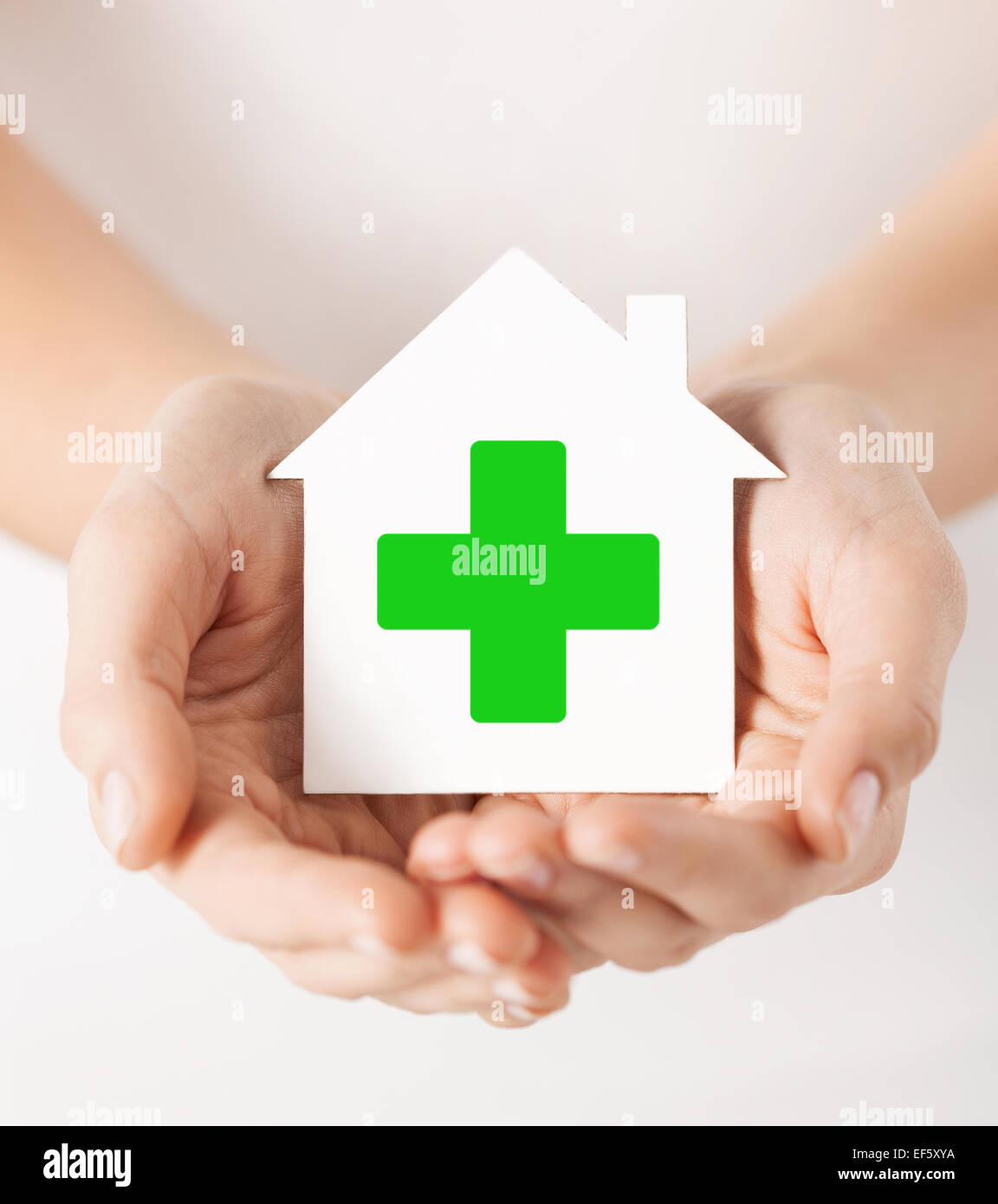 Hands holding paper house avec la croix verte Banque D'Images