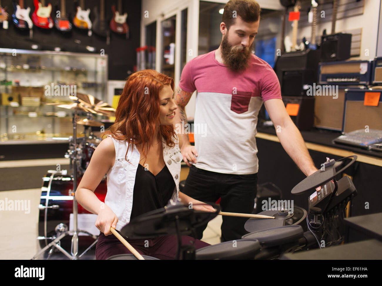 L'homme et la femme avec le kit du tambour au music store Banque D'Images