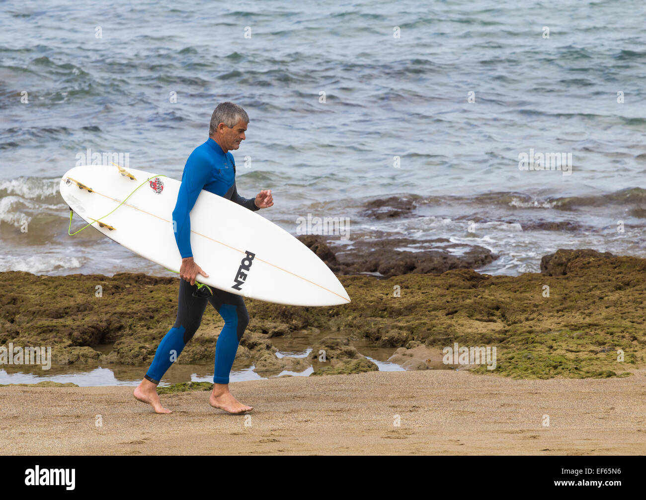 Mature surfer carrying Surfboard Banque D'Images