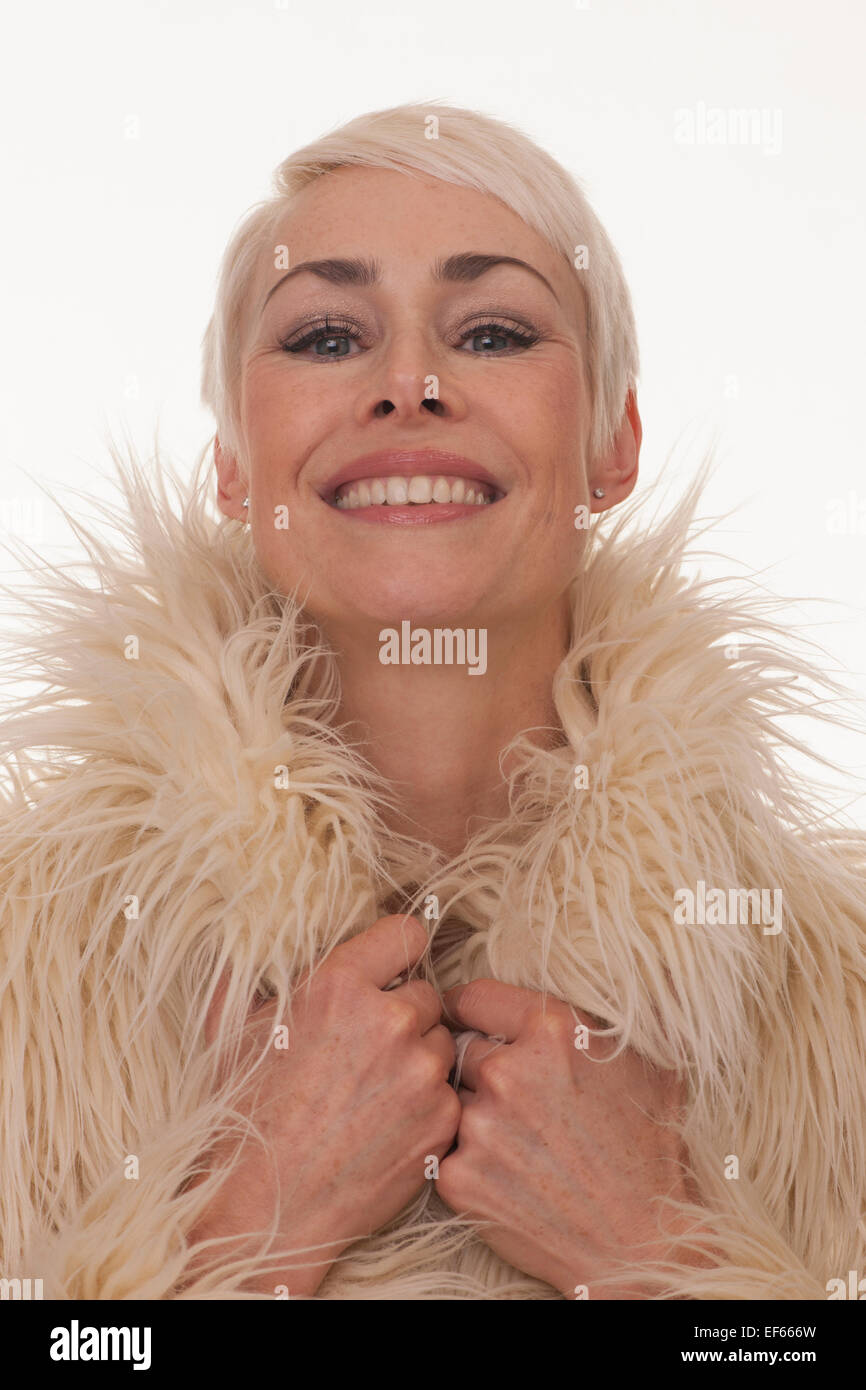 Young woman smiling holding le col de son manteau de fourrure de faux Banque D'Images