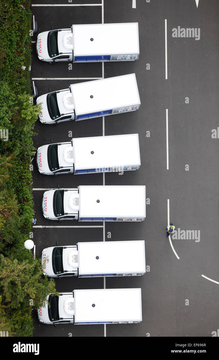 Vue aérienne d'une rangée de six Tesco home fourgonnettes de livraison avec un chauffeur devant parqué dans un magasin. Banque D'Images
