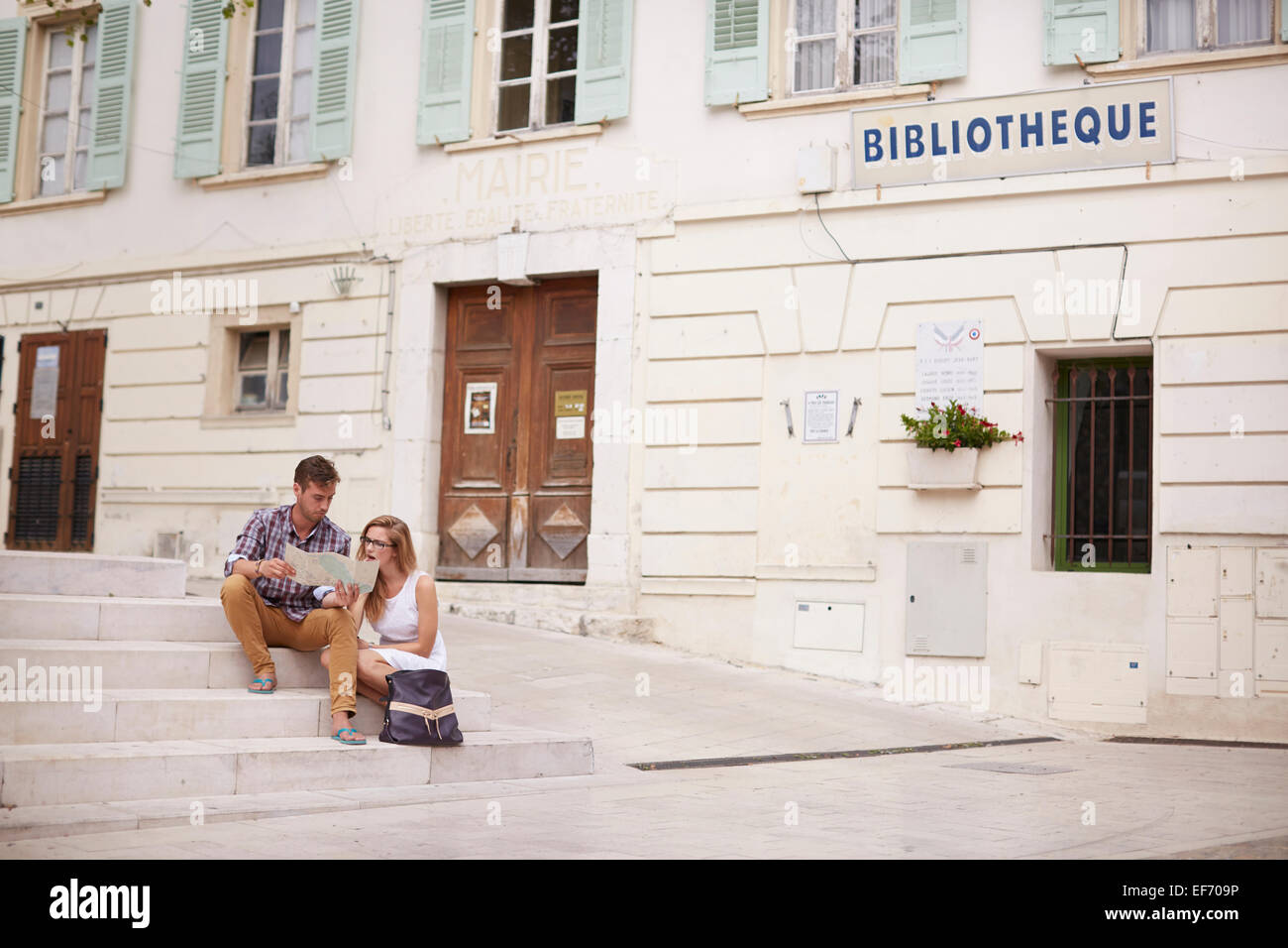Jeune couple en vacances assis par la mairie de la ville de La Colle
