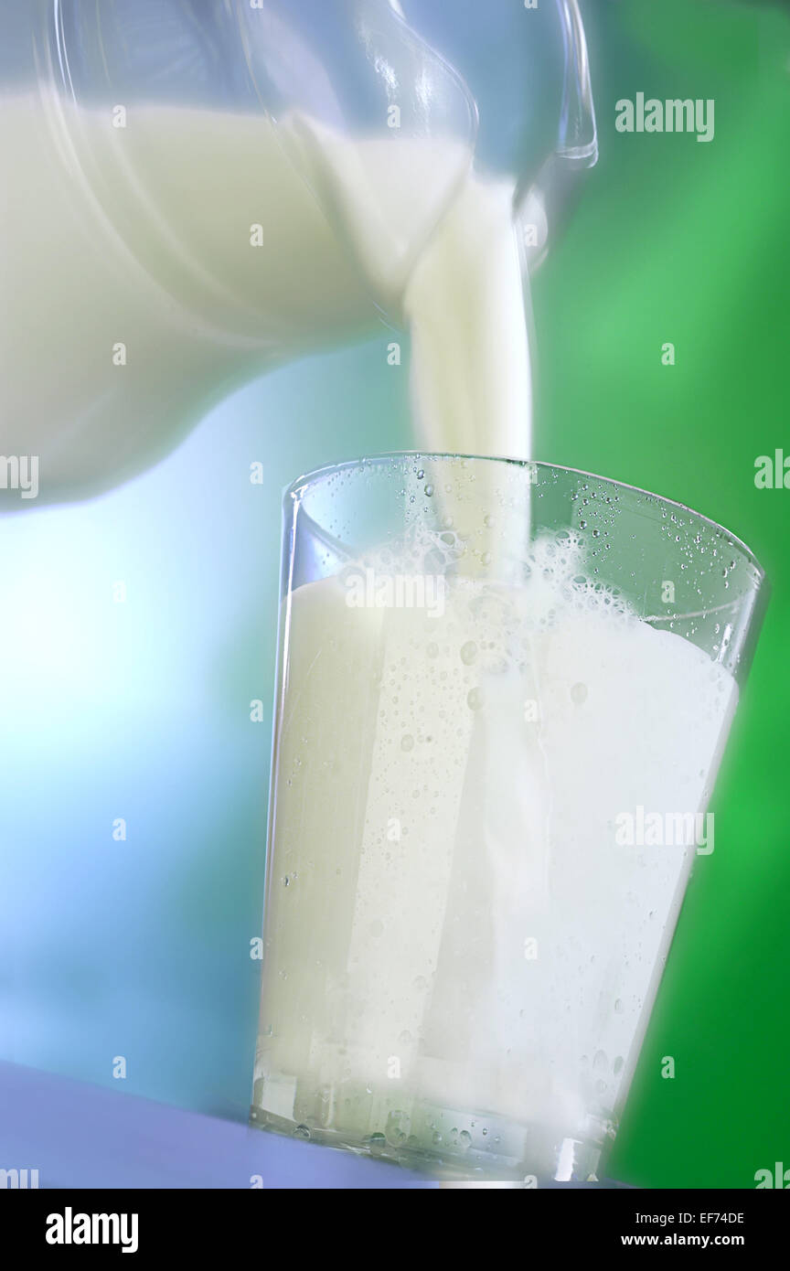 Carafe à lait découlant d'un verre de lait Banque D'Images