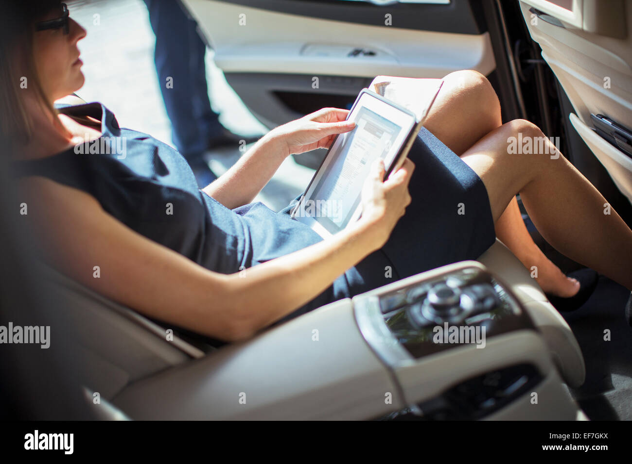 Businesswoman using digital tablet in back seat of car Banque D'Images
