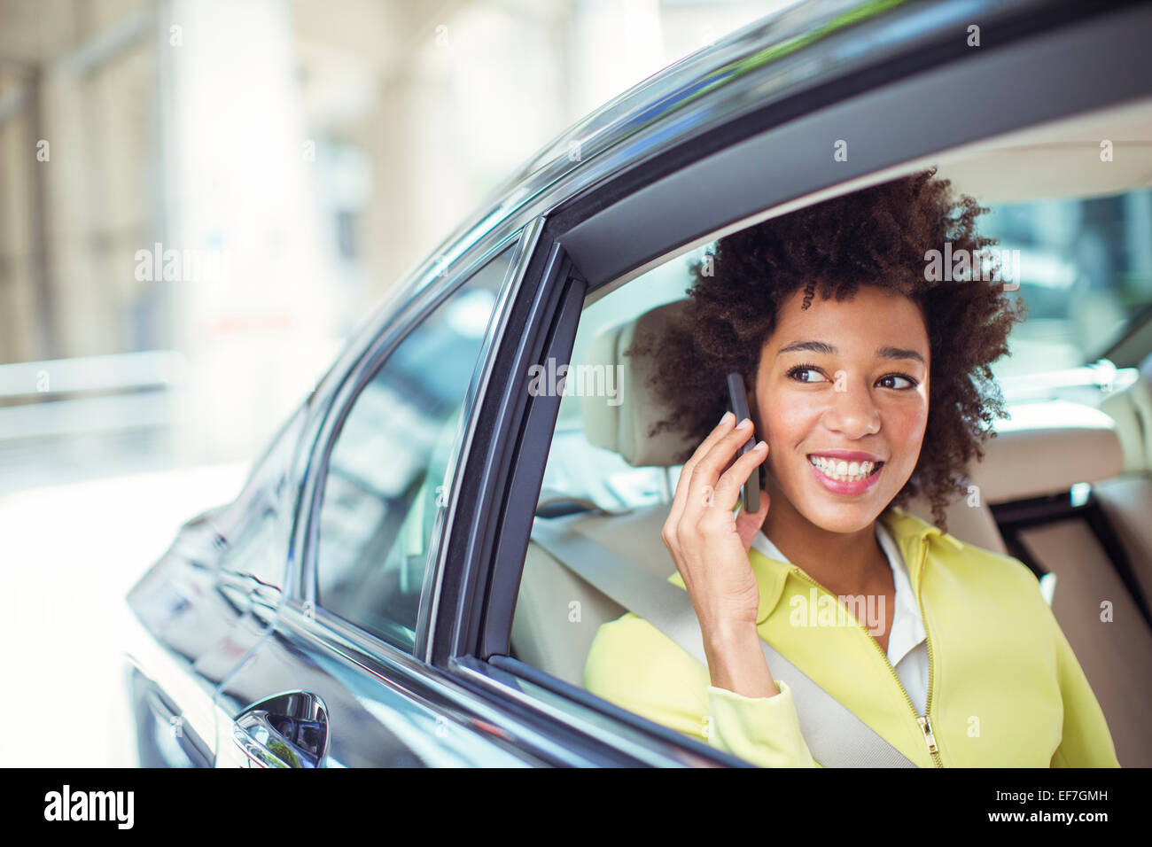 Businesswoman talking on cell phone in back seat of car Banque D'Images