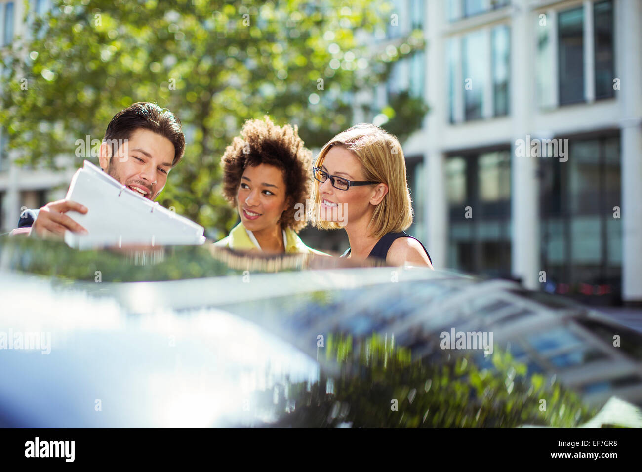 Business people reading paperwork près de voiture Banque D'Images