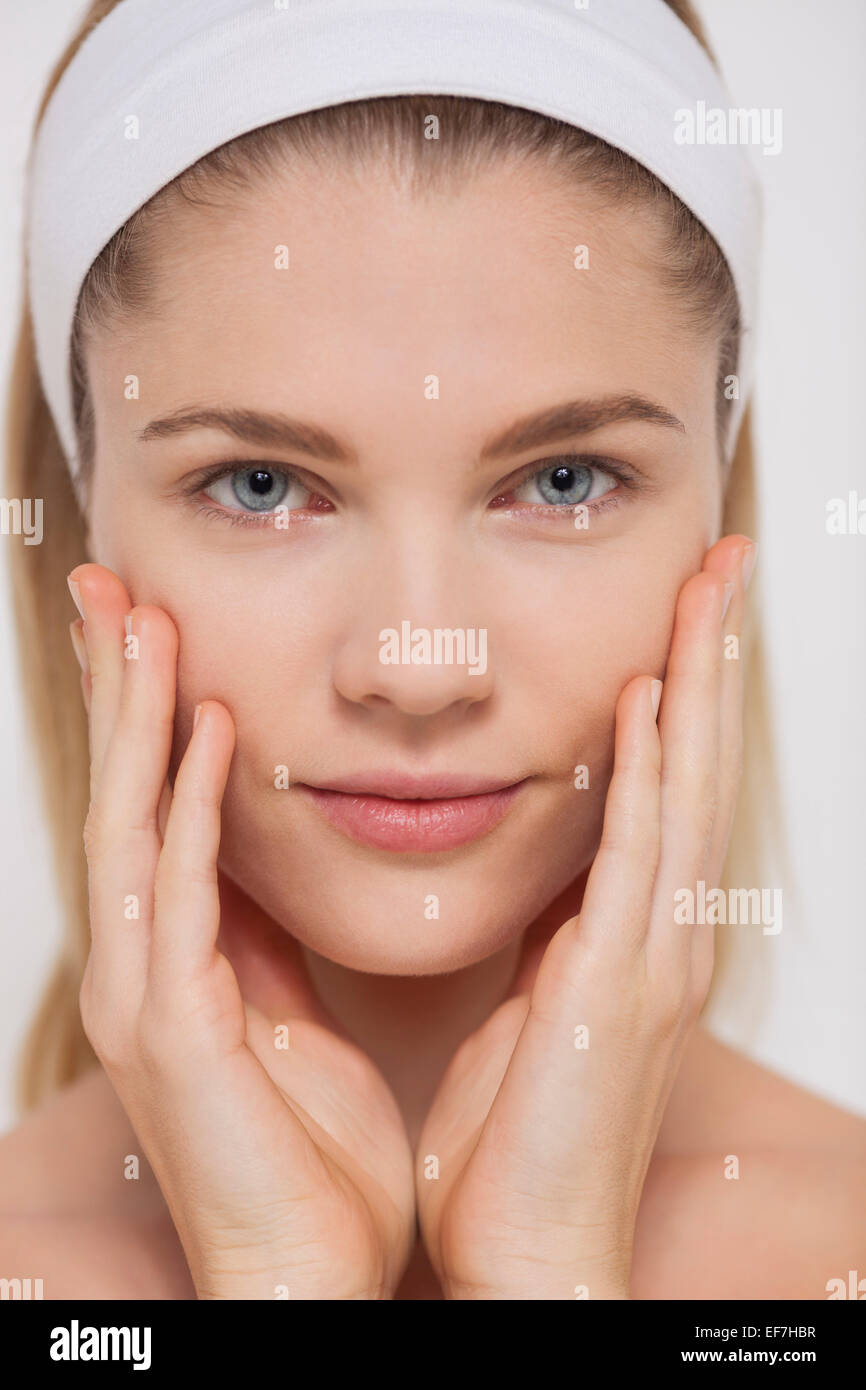 Portrait d'une belle femme de toucher ses joues Banque D'Images