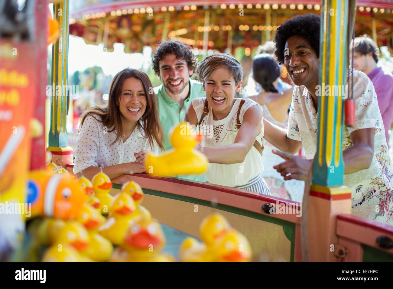 Groupe d'amis s'amusant avec le jeu de pêche en amusement park Banque D'Images