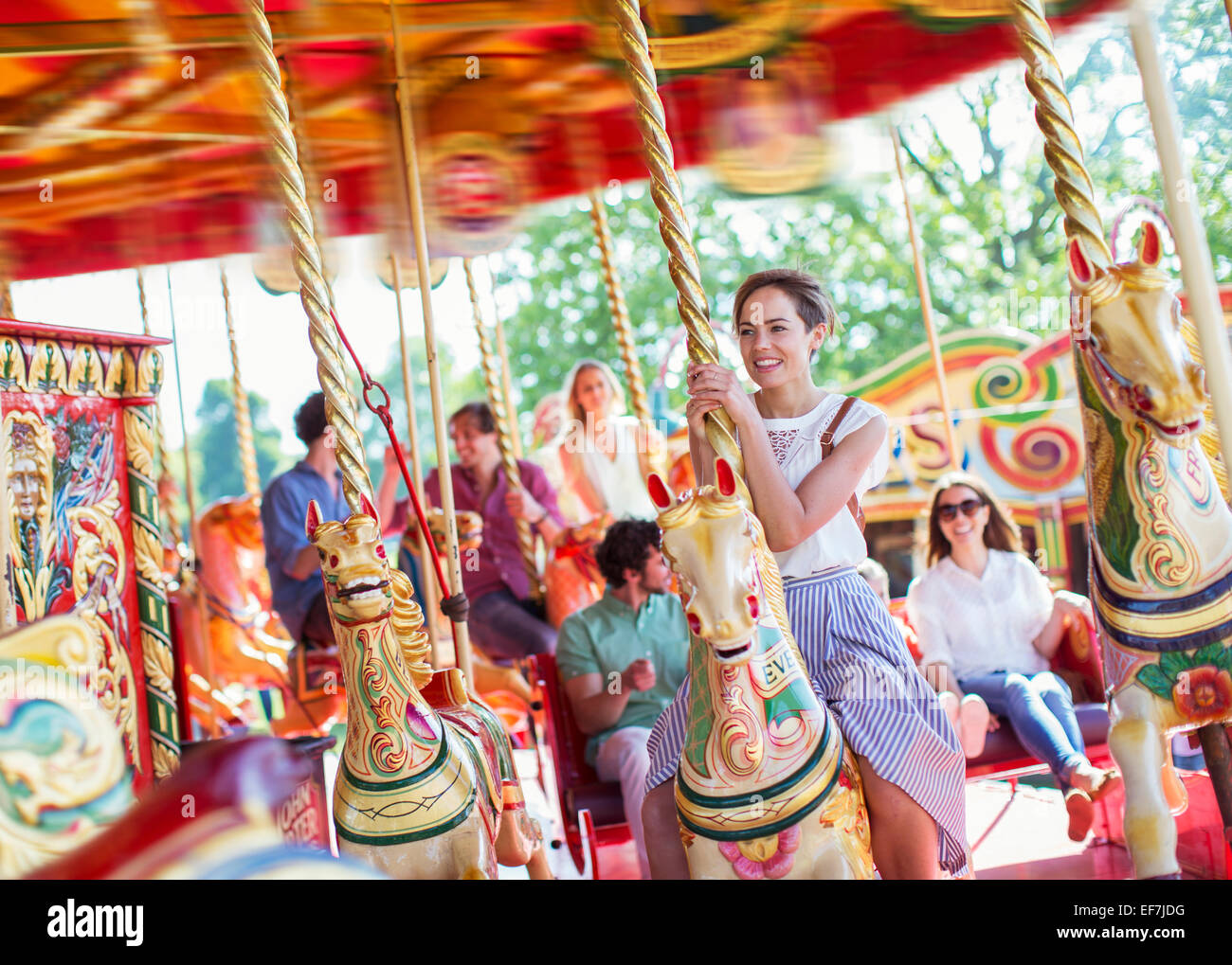 Femme assise sur le cheval de carrousel en amusement park Banque D'Images
