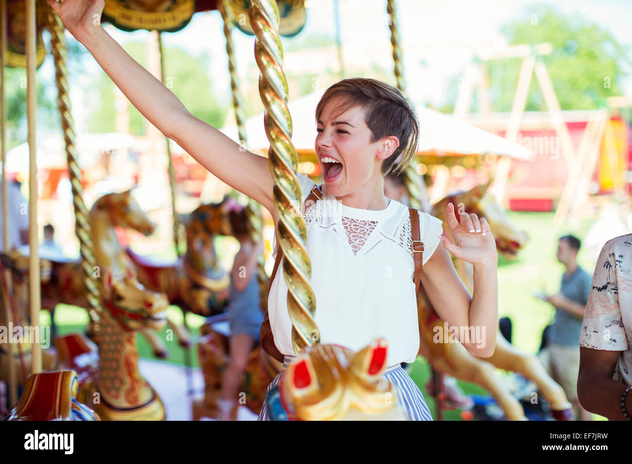 Cheerful woman sitting on horse sur carrousel en amusement park Banque D'Images