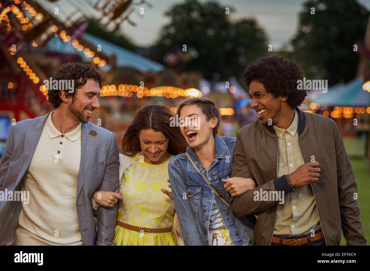 Deux couples walking in amusement park et rire au crépuscule Banque D'Images