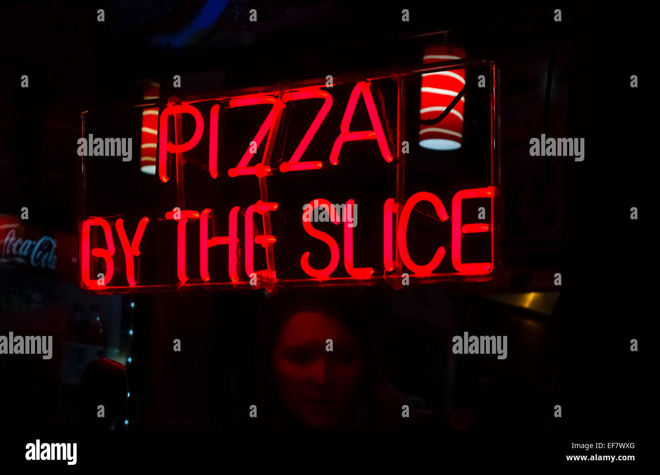 Par la tranche de pizza en néon rouge dans la fenêtre d'une boulangerie Banque D'Images