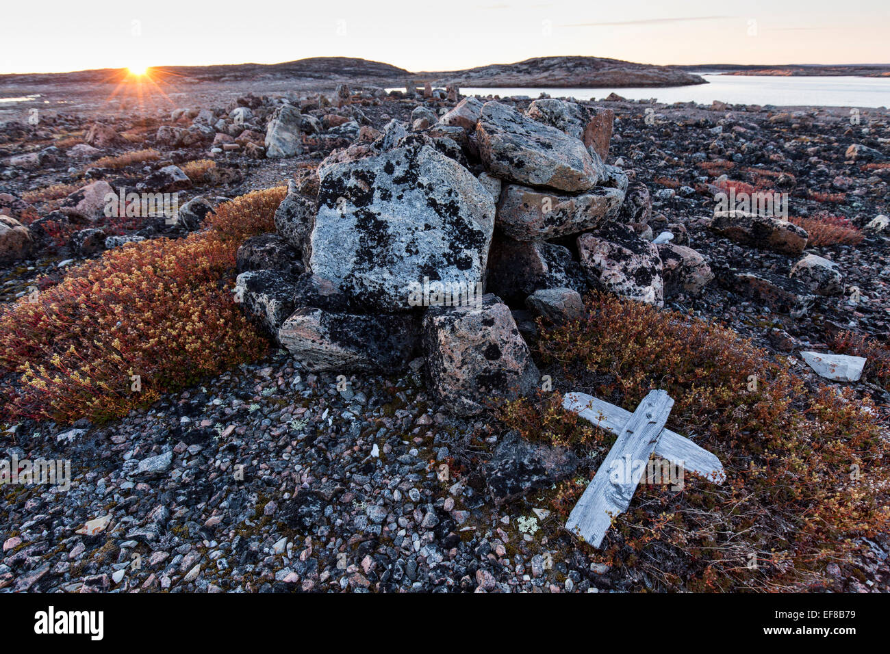 Au Canada, le Nunavut, Territoire, Setting sun lights cairn de pierre et croix de bois sur Harbour îles le long de la Baie d'Hudson près Circ de l'Arctique Banque D'Images