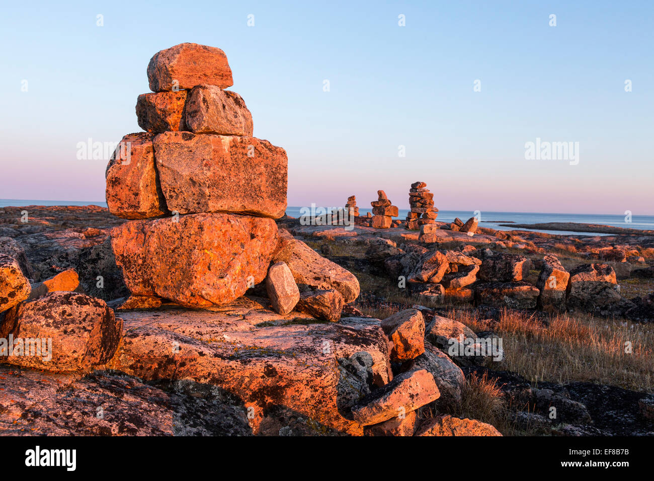 Au Canada, le Nunavut, Territoire, Setting sun lights cairn de pierre et croix de bois sur Harbour îles le long de la Baie d'Hudson près Circ de l'Arctique Banque D'Images