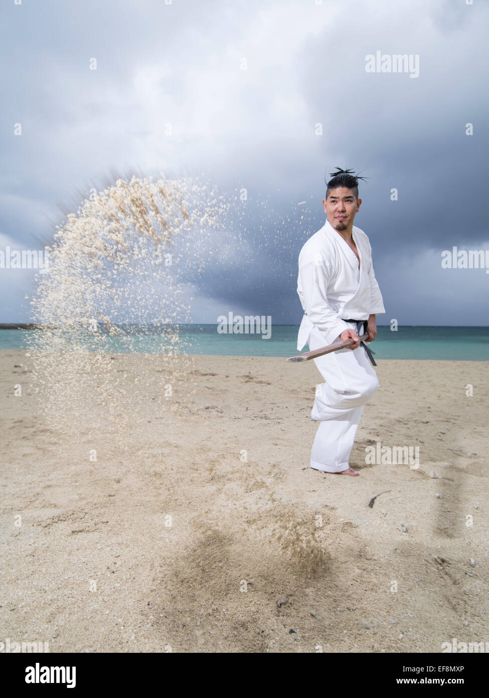 Fumiya Matayoshi Kobudo en formation / sur la plage de karaté à Okinawa au Japon. Utilisation de l'eku (rame ) pour feuilleter en face des adversaires de sable Banque D'Images