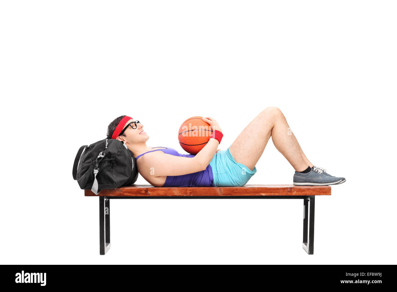 Jeune homme allongé sur un banc et holding basketball isolé sur fond blanc Banque D'Images