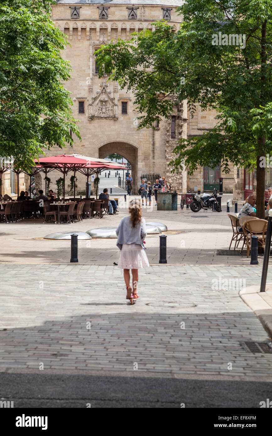 Une petite fille sur un scooter rides vers Calihau Gate, l'architecture historique à Bordeaux en France. Banque D'Images