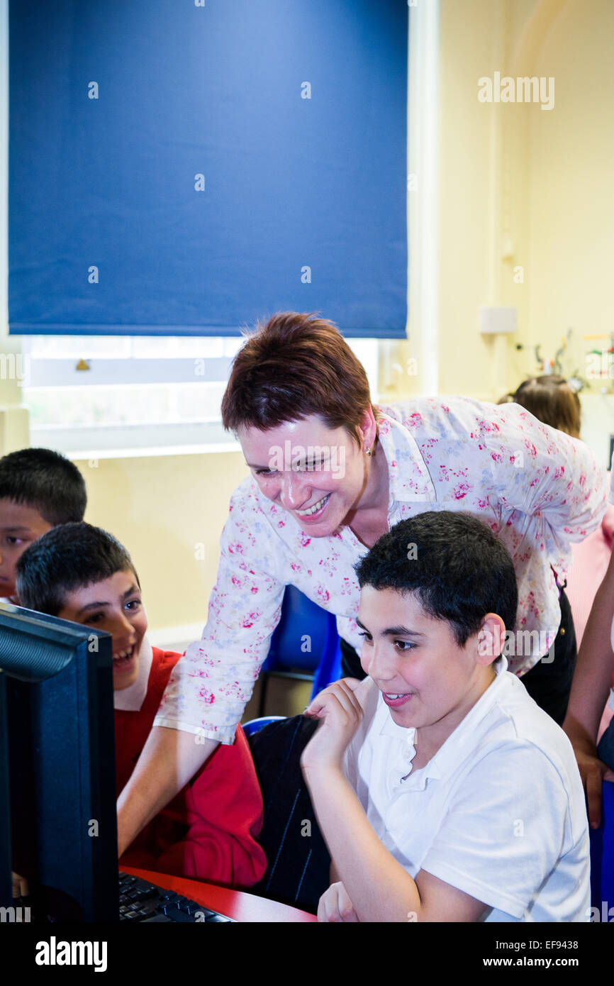 Les élèves enseignants montrant comment écrire un petit morceau de code pour l'ordinateur. L'école primaire,London,UK Banque D'Images
