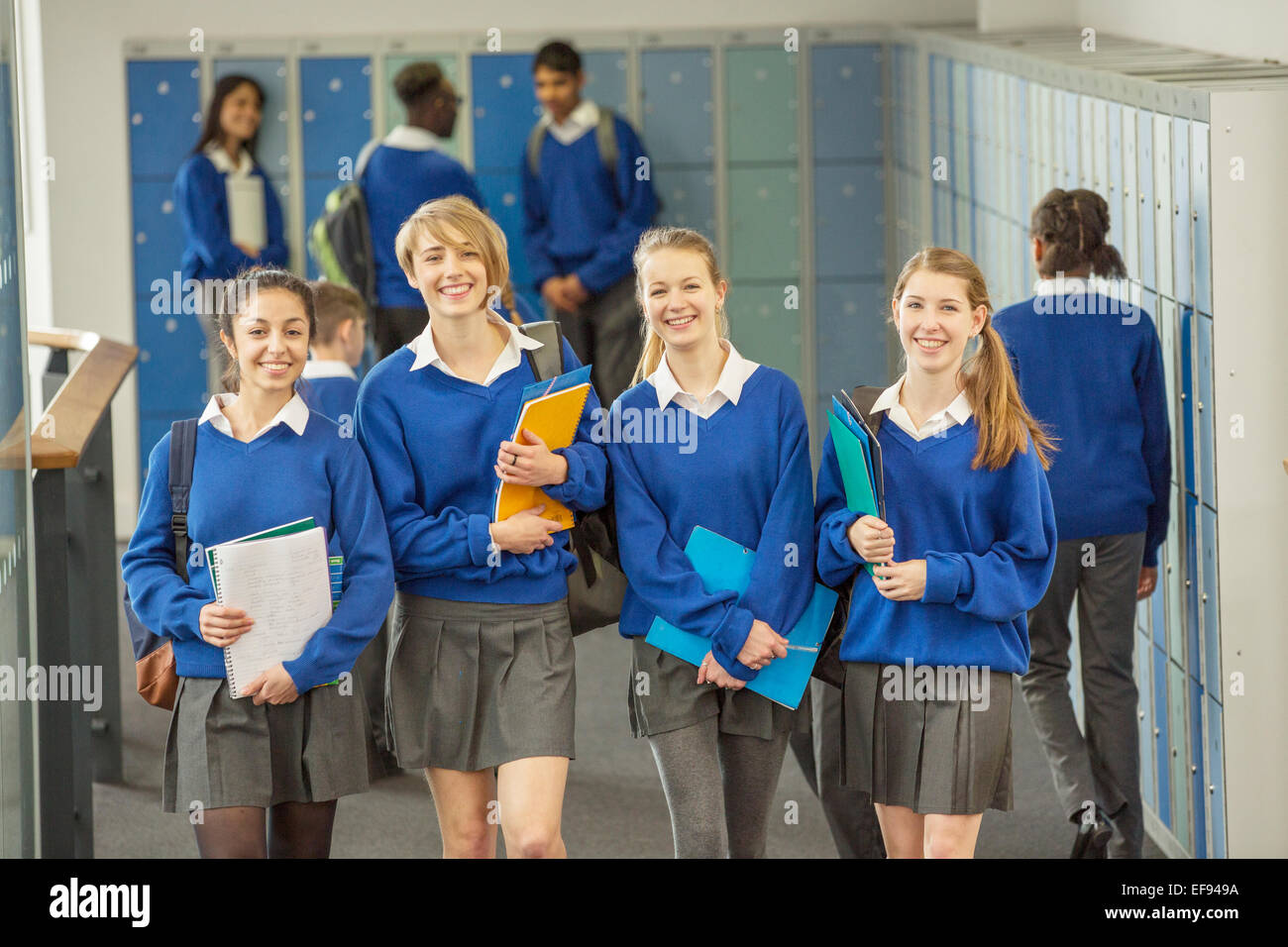 Portrait of smiling étudiantes portant des uniformes scolaires walking through school corridor Banque D'Images