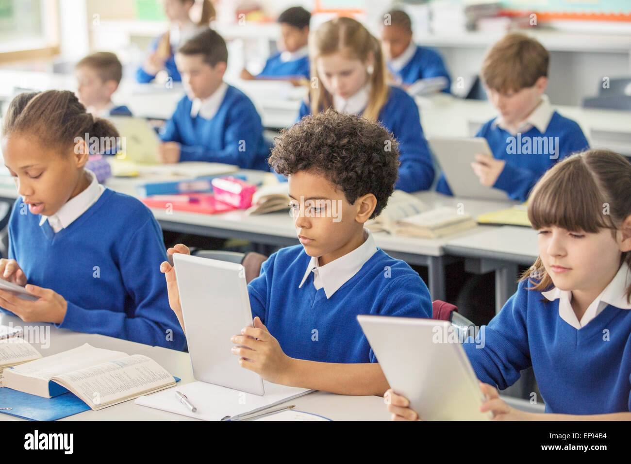 Les enfants de l'école élémentaire avec digital tablets in classroom Banque D'Images