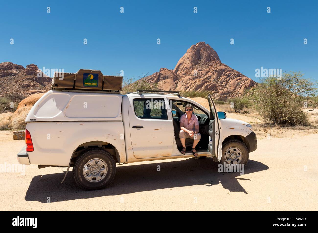 Une femme s'arrête pour une photo à la montagne Spitzkoppe, Namibie, Afrique. La femme faisait partie d'un couple sur une voiture maison de vacances. Banque D'Images