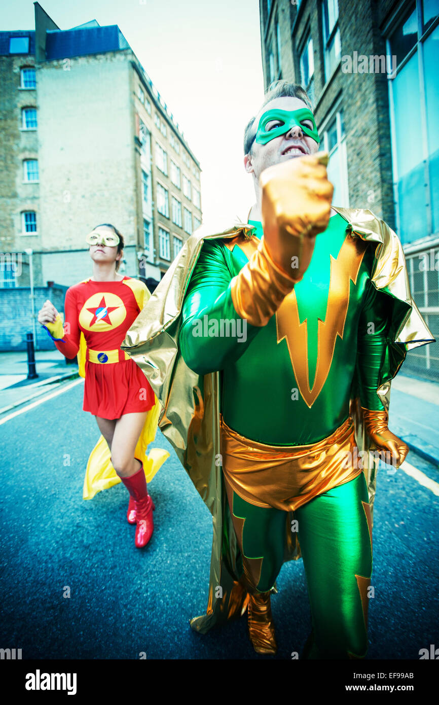 Couple de super-héros running on city street Banque D'Images