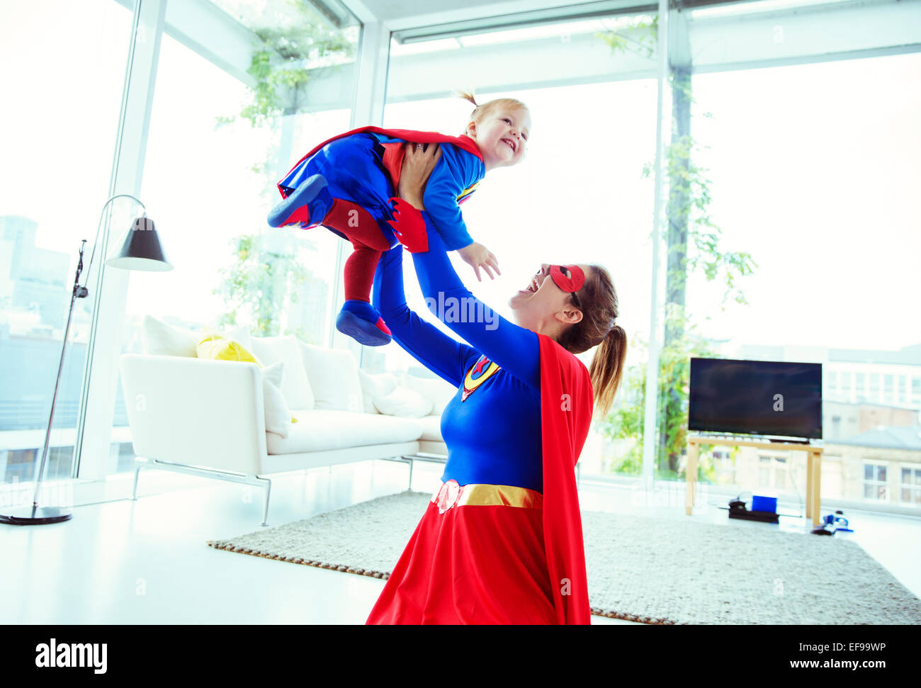 Jouer super-héros avec bébé dans la salle de séjour Banque D'Images