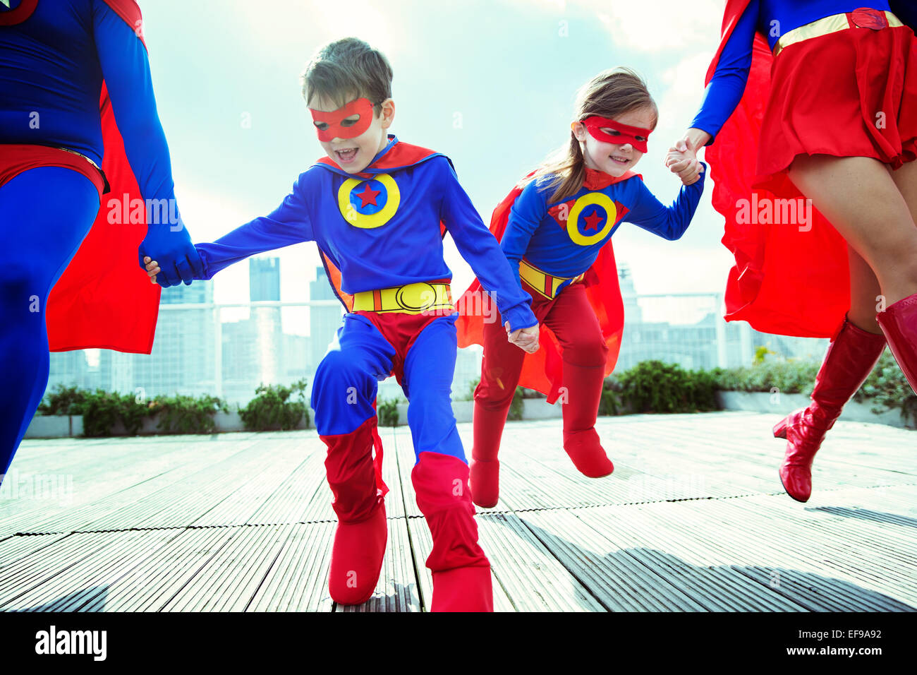 Famille de super-héros s'exécutant sur les toits de la ville Banque D'Images