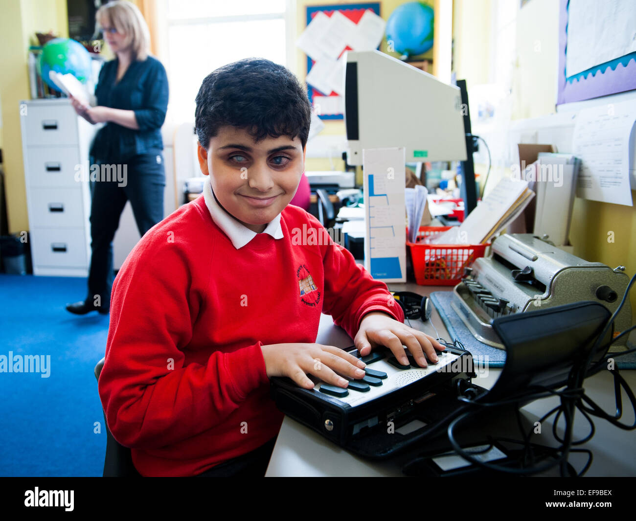 Un garçon aveugle à l'aide de machine braille à besoins spéciaux dans la classe de l'école primaire de Londres Banque D'Images
