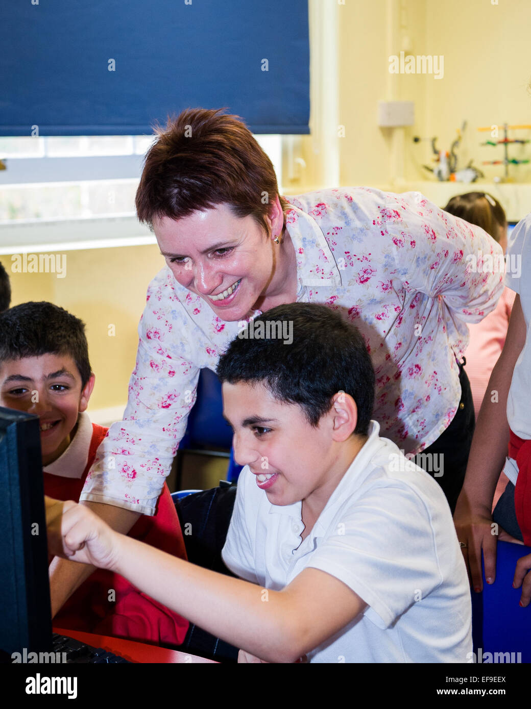 Les élèves enseignants montrant comment écrire un petit morceau de code pour l'ordinateur. L'école primaire,London,UK Banque D'Images