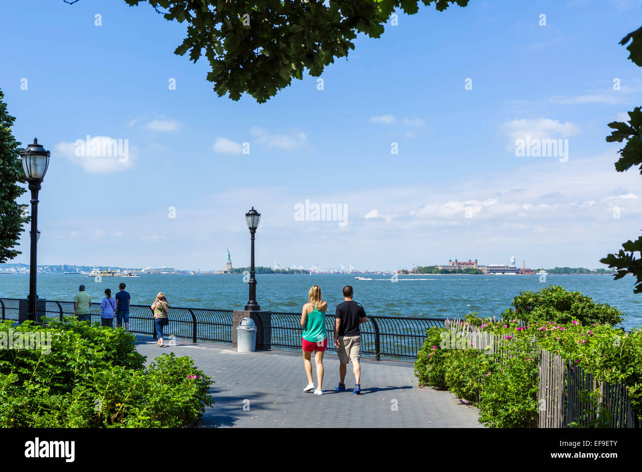 Esplanade dans Battery Park City avec Ellis Island et la Statue de la liberté à distance, Lower Manhattan, NYC, New York, NY, USA Banque D'Images