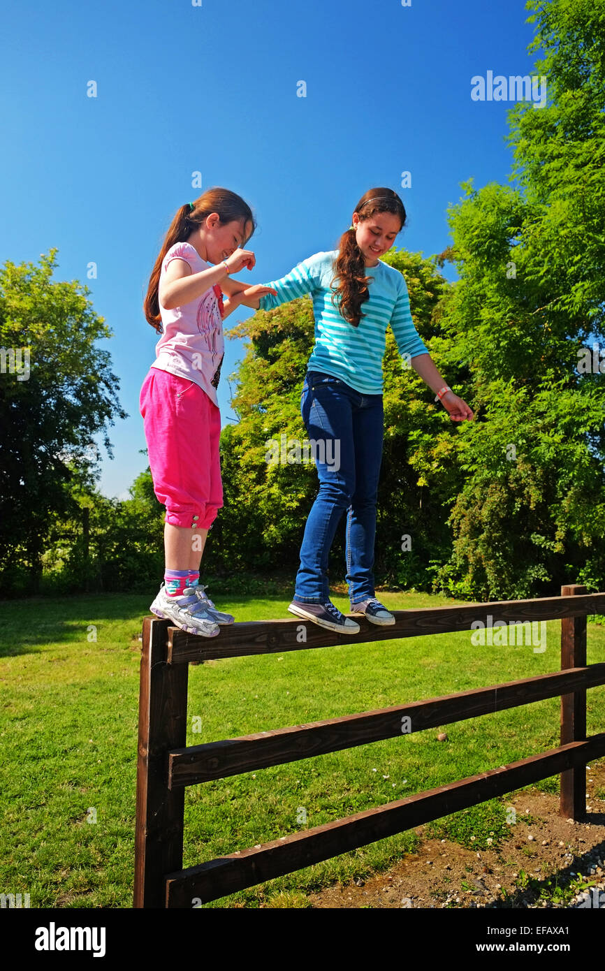 Deux jeunes sœurs corde marche sur une clôture dans le nord du comté de Dublin, Irlande Banque D'Images