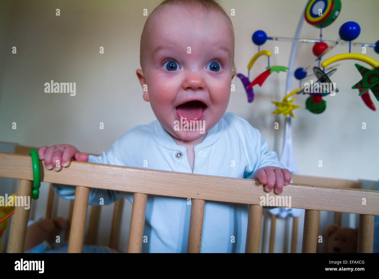 Bébé ou jeune enfant souriant et sautant de lit bébé Banque D'Images