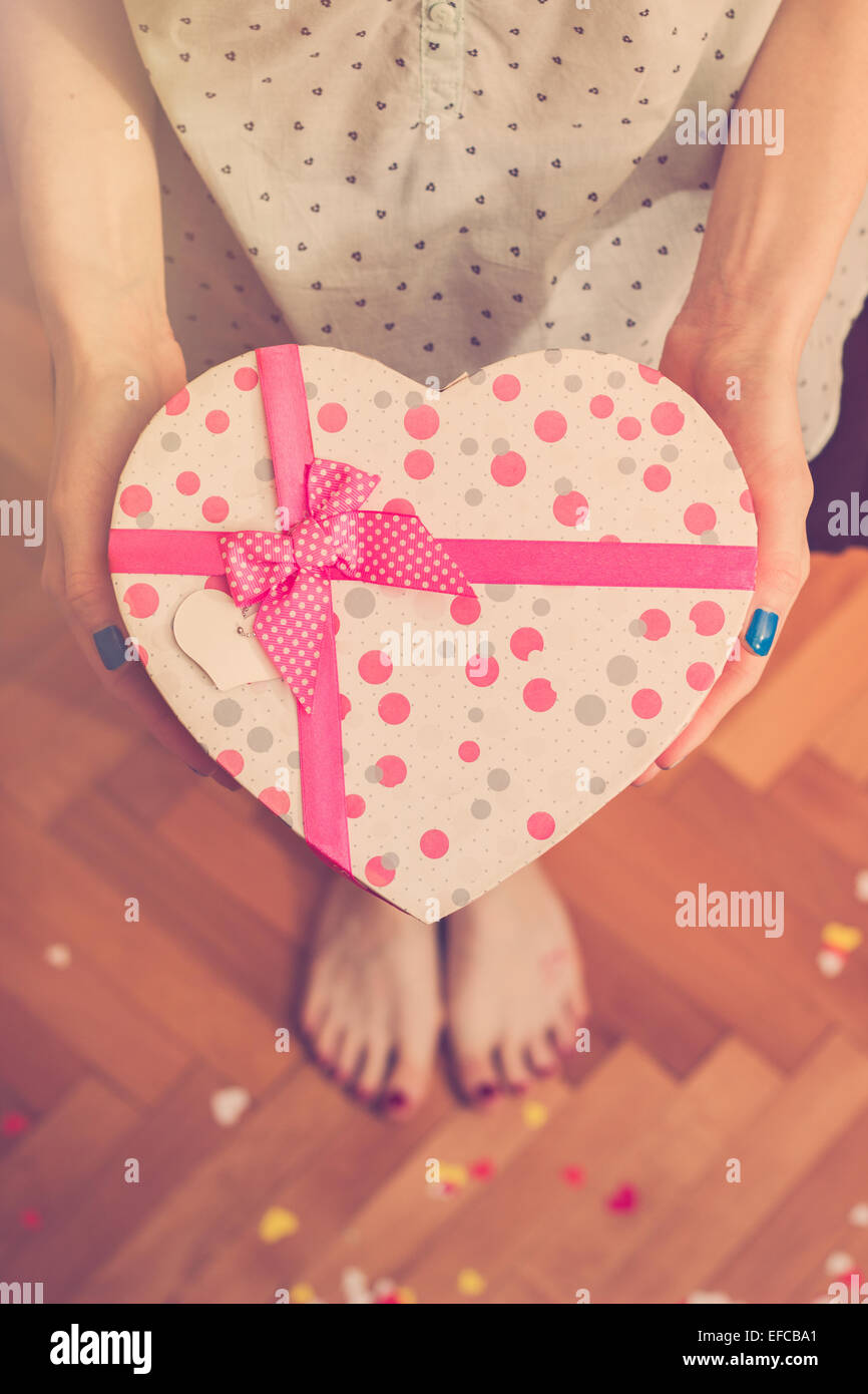 Girl's hands holding heart shaped gift box. Couleurs rétro Banque D'Images