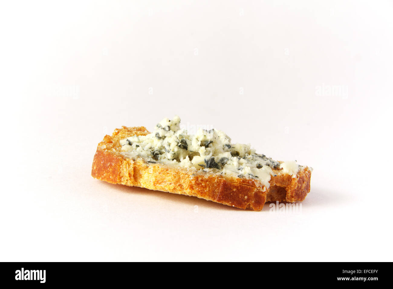Un canapé de fromage bleu sur une tranche de baguette grillées sur fond blanc avec éclairage studio Banque D'Images