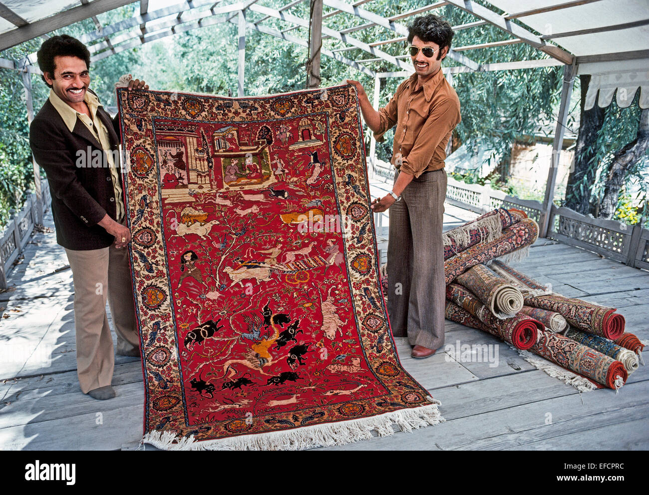 Deux vendeurs Kashmiri fièrement tissés à la main traditionnelle de tapis orientaux aux visiteurs à le lac Dal à Srinagar dans l'Inde de la région du Cachemire. Banque D'Images