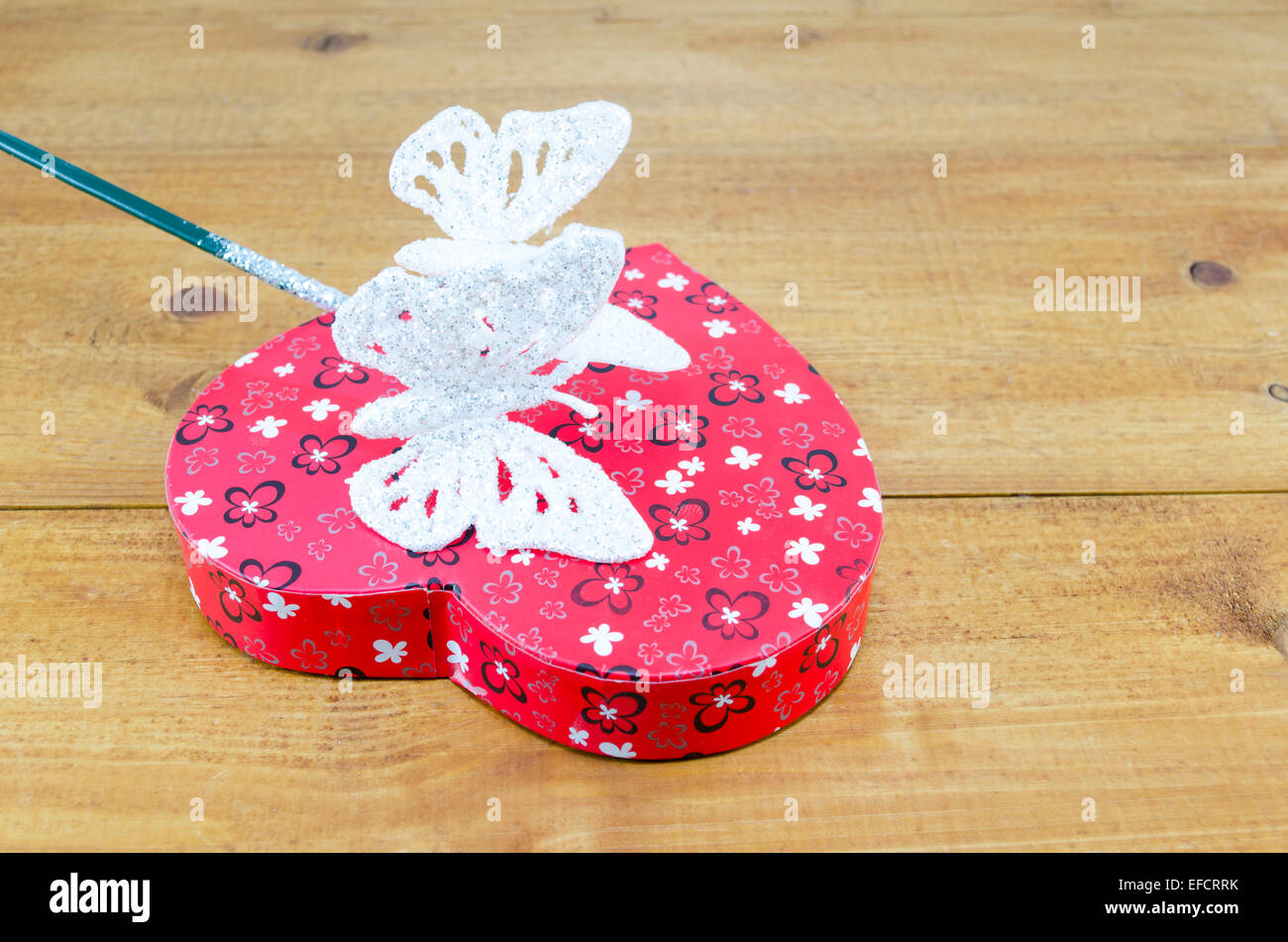 Boîte en forme de coeur et un coup de baguette magique en forme de papillon sur une table en bois Banque D'Images