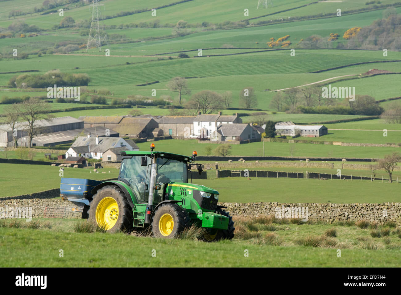 6126r John Deere répandre engrais sur les pâturages de montagne, Lancashire, Royaume-Uni. Banque D'Images