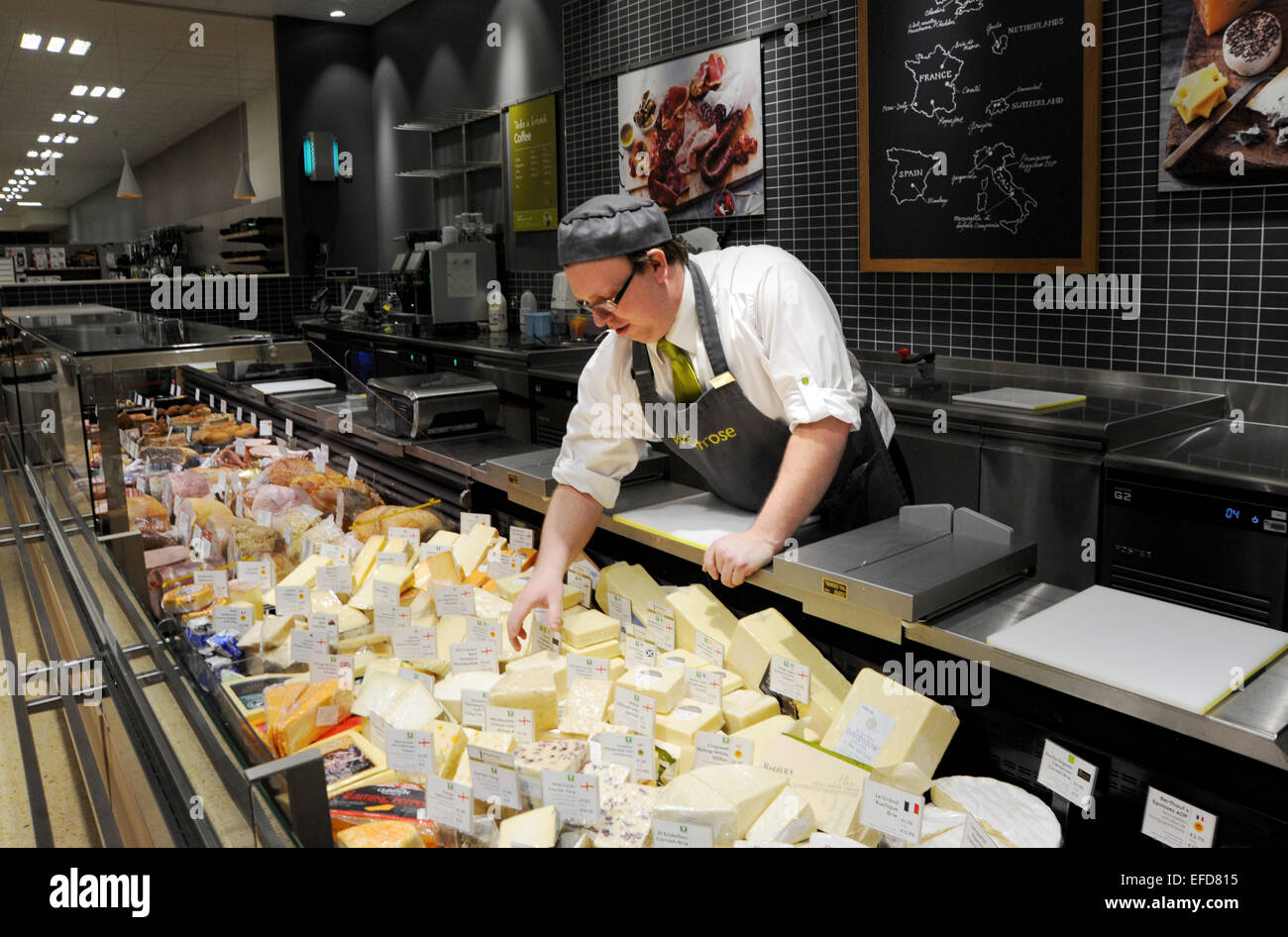 Jeune homme travaillant sur les fromages dans un supermarché Waitrose UK Banque D'Images