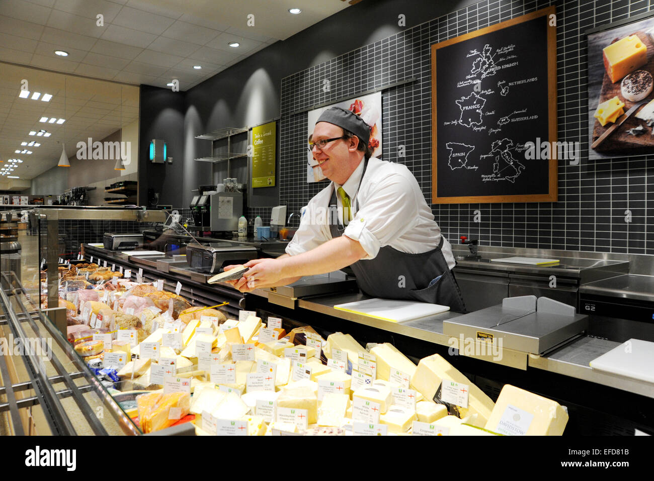 Jeune homme travaillant sur les fromages dans un supermarché Waitrose UK Banque D'Images